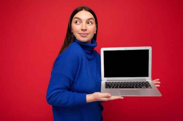 Foto de retrato de uma bela jovem morena segurando um laptop e olhando para o lado