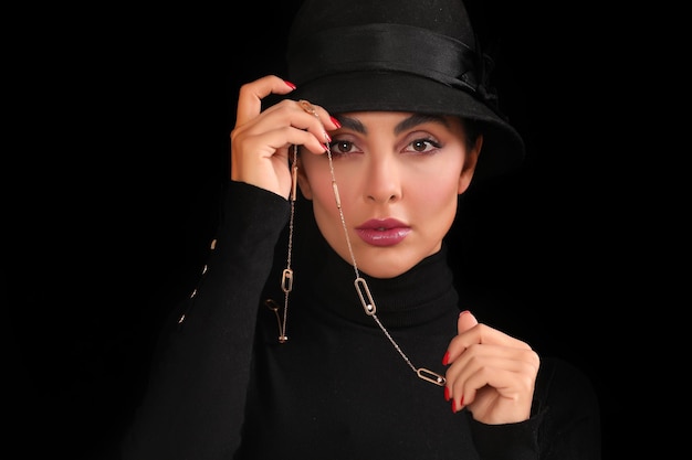 Foto de retrato de uma garota encantadora com um colar na frente do rosto com chapéu preto