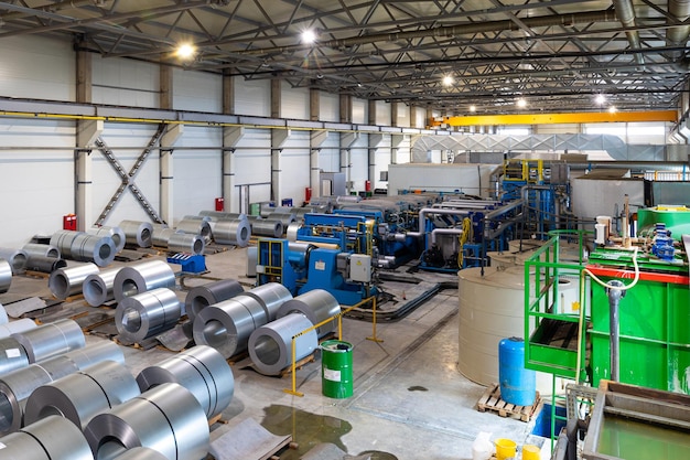 Foto de rolo de chapa de aço galvanizado pintado na máquina de corte, serralheria e serralheria na fábrica. Máquina industrial para corte de bobinas de telhado de chapa metálica.