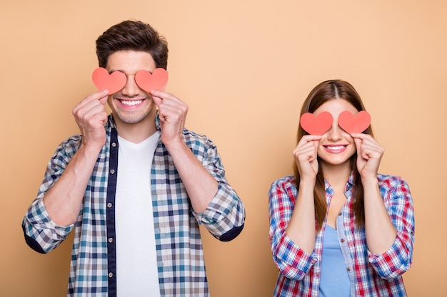 Foto de ruivo vermelho fofo positivo casal encantador casual de duas pessoas segurando cartões postais dos namorados com as mãos cobrindo os olhos isolados sobre um fundo bege