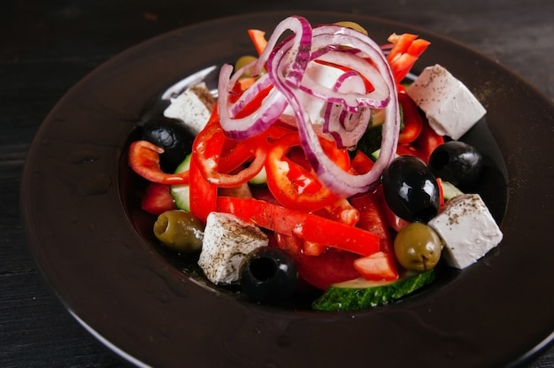 Foto de salada grega em uma placa preta.