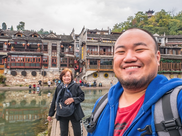 Foto de selfie de um viajante asiático em família com vista panorâmica da cidade velha de fenghuang