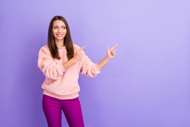 Foto de senhora indicando o lado dos dedos olhando o espaço vazio na parede violeta