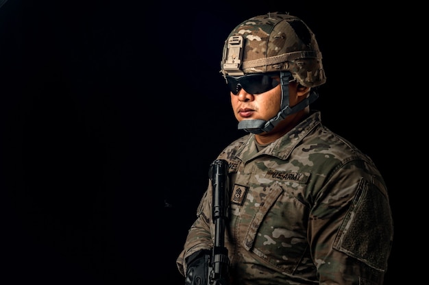 Foto de soldado em fundo preto. soldado das forças especiais dos estados unidos ou empreiteiros militares privados segurando um rifle. imagem em fundo preto. soldado, exército, guerra, arma e conceito de tecnologia.