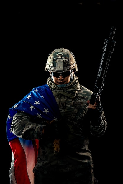 Foto de soldado segurando a bandeira dos EUA no fundo. Soldado dos Estados Unidos da força especial ou empreiteiros militares segurando um rifle. Imagem de fundo. soldado, exército, guerra, arma e conceito de tecnologia.