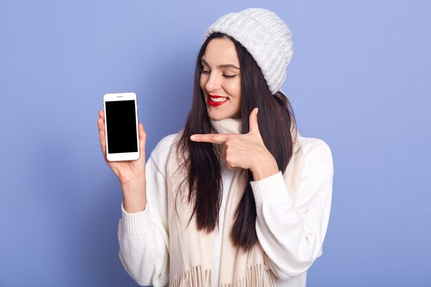 Foto de sorridente boa aparência jovem segurando o smartphone com tela em branco