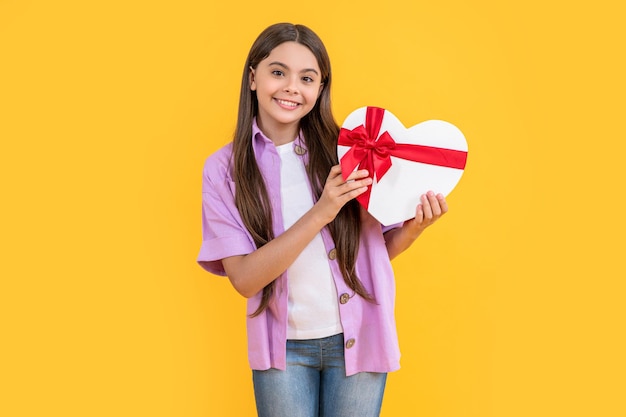 Foto de sorriso de menina adolescente com caixa de presente de aniversário menina adolescente com presente de aniversário isolada em amarelo