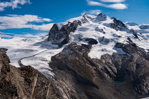 Foto de tirar o fôlego das montanhas rochosas cobertas de neve sob um céu azul