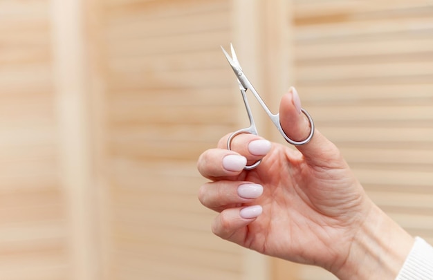 Foto de tratamento de beleza de manicure de unhas de mulher bem cuidada Mãos segurando uma tesouraxDxA