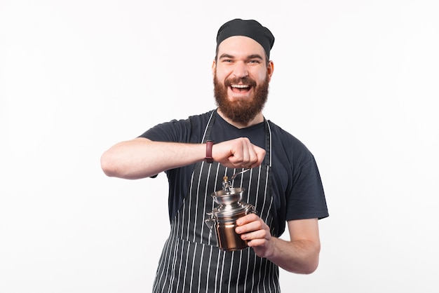 Foto de um barista sorridente moendo alguns grãos de café com um moedor de café