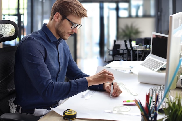 Foto de um belo arquiteto masculino trabalhando em um projeto em seu escritório