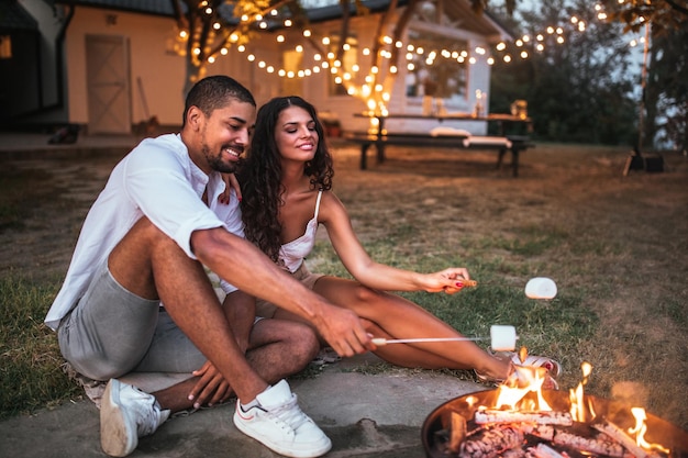 Foto de um belo casal assando marshmallows no quintal