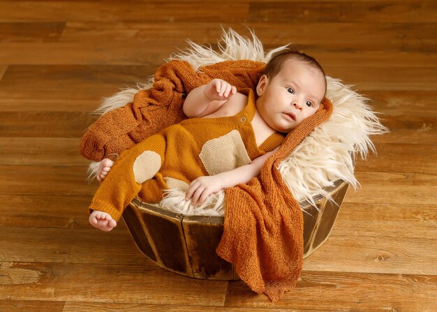 Foto foto de um bonito bebê asiático de 1 mês vestindo um cobertor de coágulo laranja