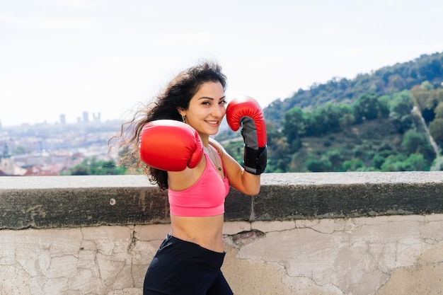 Foto de um boxeador de mulher forte aptidão em luvas posando ao ar livre.