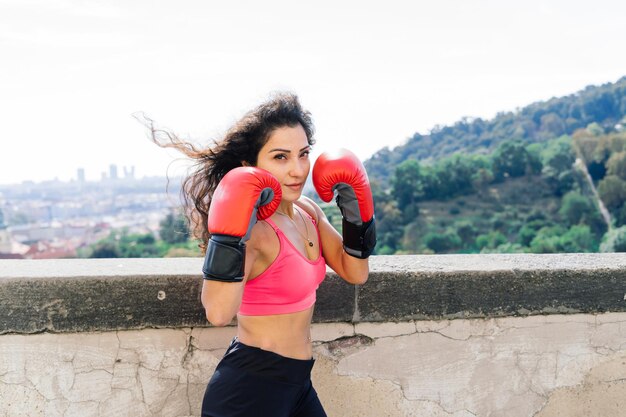 Foto de um boxeador de mulher forte aptidão em luvas posando ao ar livre.