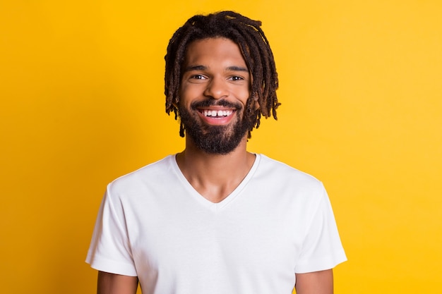 Foto de um cara amigável de pele escura sorrindo sorrindo e vestindo uma camiseta casual com fundo de cor amarela