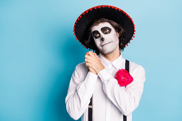 Foto de um cara engraçado zumbi criatura dia da morte, mascarada de maquiagem assustadora, sonhador, olhar para cima, braços juntos, acho que noiva morta catrina calavera usar traje de chapéu latino isolado fundo de cor azul