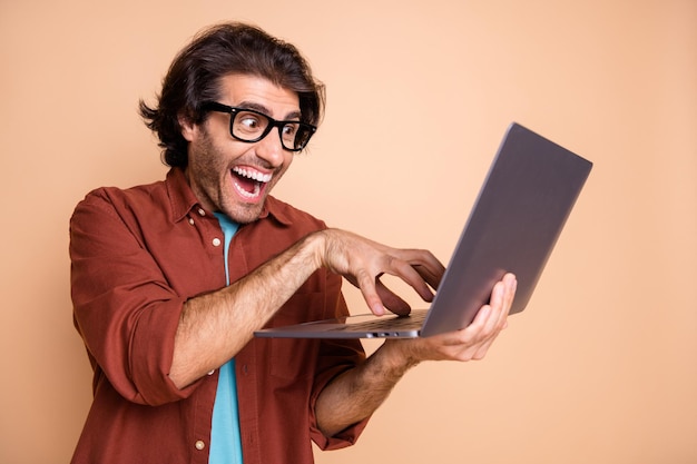 Foto de um cara malvado rindo, digitando isolado em um fundo bege pastel