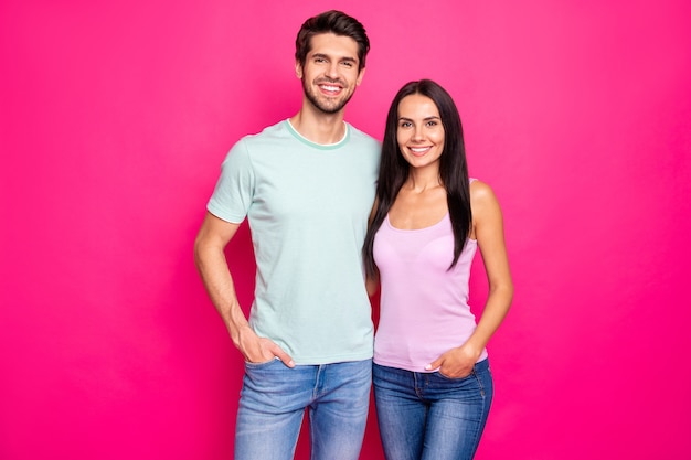 Foto de um casal incrível, abraçando-se, apreciando a melhor empresa, vestindo roupas casuais isoladas de fundo de cor rosa brilhante