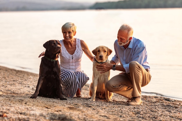 Foto de um casal sênior feliz e seus cães à beira do rio