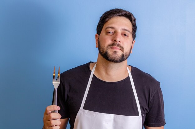 Foto de um chef feliz segurando um utensílio para cozinhar carne