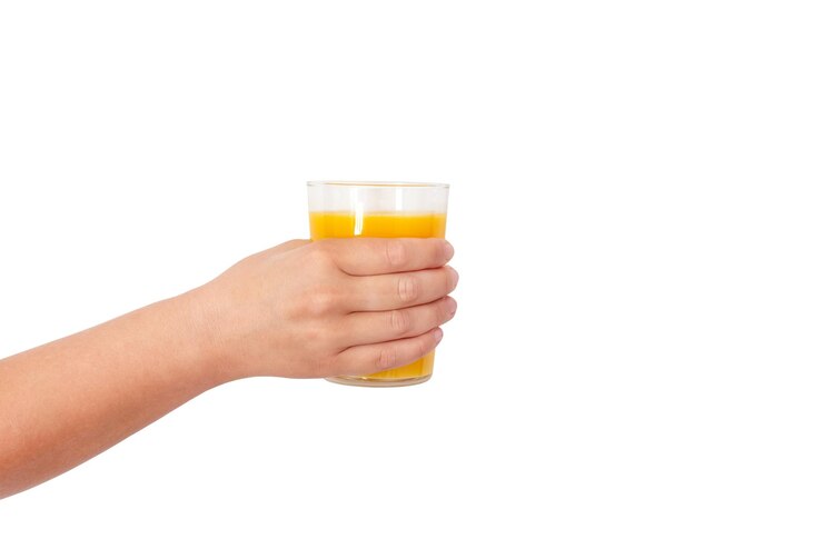 Foto foto de um copo com suco de laranja à disposição em um fundo claro