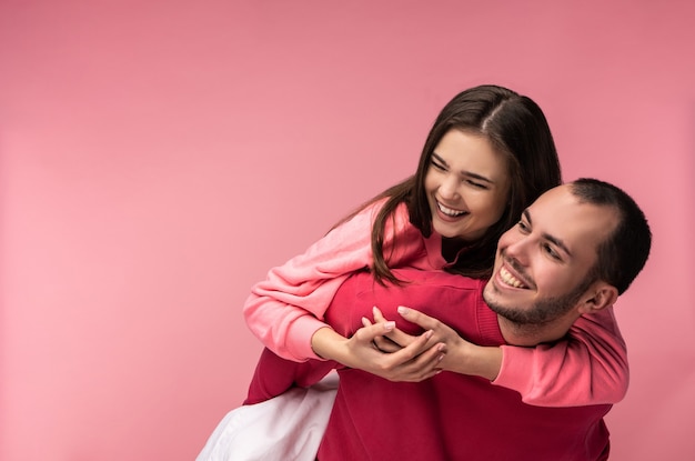 Foto de um doce casal se abraça e sorria. Macho e fêmea estão apaixonados, isolados sobre fundo rosa.