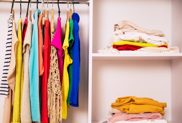 Foto de um guarda-roupa grande com compartimento branco cheio de roupas, sapatos e caixas, que estão na ordem perfeita nas prateleiras