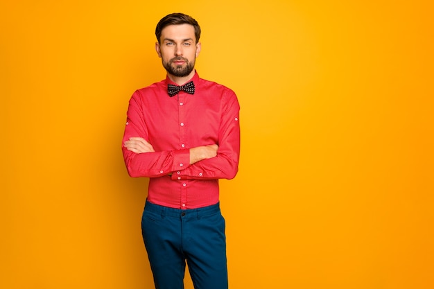 Foto de um homem atraente homem de negócios com os braços cruzados, pessoa autoconfiante, trabalhador vestindo uma camisa vermelha elegante com calça azul de gravata borboleta preta