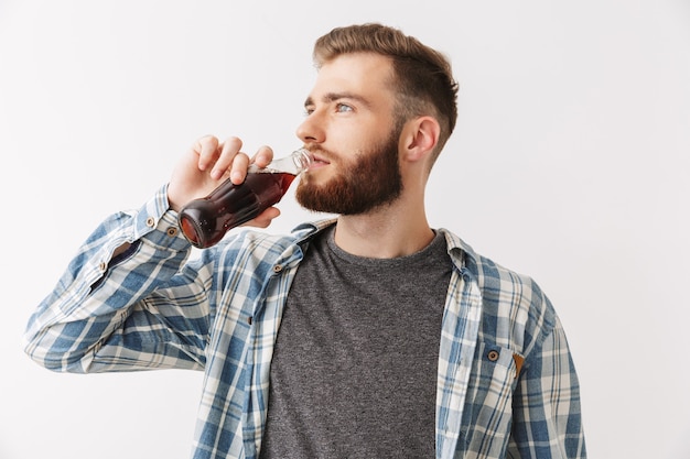 Foto de um homem barbudo satisfeito com uma camisa bebendo refrigerante