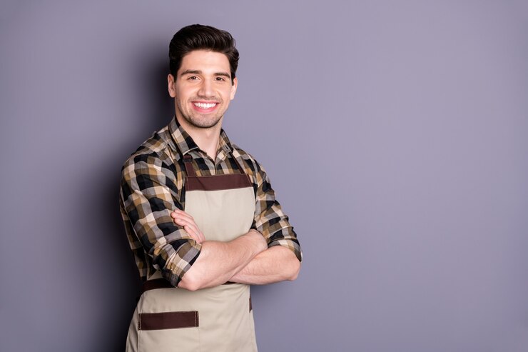 Foto de um homem bonito, alegre e confiante com os braços cruzados, sorriso inteligente, inteligente, isolado na parede cinza