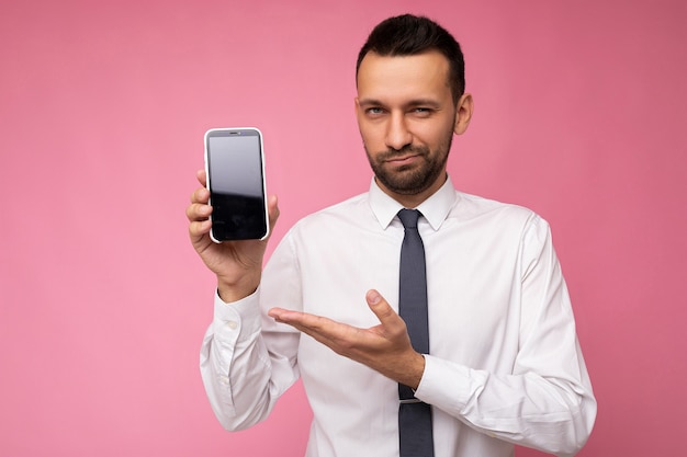 Foto de um homem bonito e autoconfiante, vestindo camisa branca casual e gravata isolada em rosa