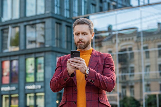 Foto de um homem enviando mensagens no smartphone de jaqueta homem enviando mensagens no smartphone