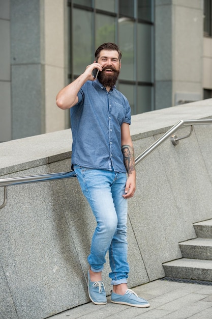 Foto de um homem feliz conversando em um smartphone falando de um homem em um smartphone ao ar livre