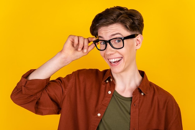 Foto foto de um jovem alegre confiante com visão de óculos de toque de mão isolada sobre fundo de cor amarela