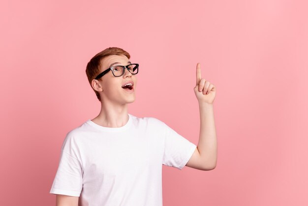 Foto de um jovem animado apontando o dedo para ter uma ideia, escolher olhar, um espaço vazio isolado sobre um fundo de cor rosa