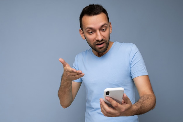 Foto de um jovem bonito com barba usando uma camiseta azul do dia a dia isolada sobre um fundo azul