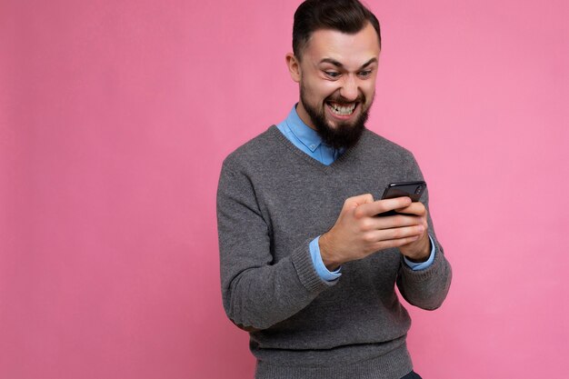 Foto de um jovem bonito, muito feliz, emocional e de boa aparência, vestindo um estilo casual elegante