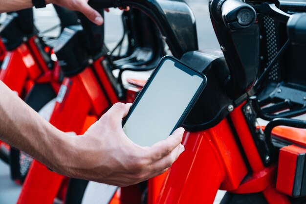 Foto foto de um jovem branco irreconhecível reservando uma bicicleta alugada com seu telefone inteligente