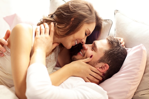 Foto de um jovem casal se beijando na cama