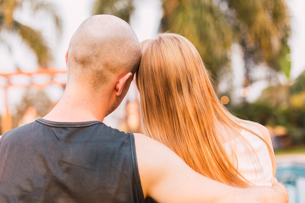 Foto de um jovem casal sentado em um banco de costas um para o outro