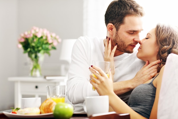 Foto de um jovem casal tomando café da manhã na cama