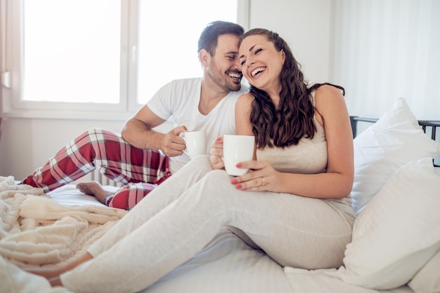 Foto de um jovem casal tomando café na cama