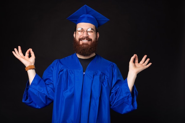 Foto de um jovem estudante de solteiro azul mostrando um gesto zen