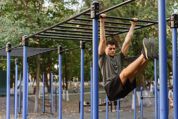 Foto de um jovem fazendo mergulhos nas barras irregulares.