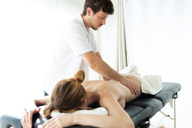 Foto de um jovem fisioterapeuta fazendo um tratamento nas costas de um paciente em uma sala de fisioterapia. Reabilitação, massagem médica e conceito de terapia manual.