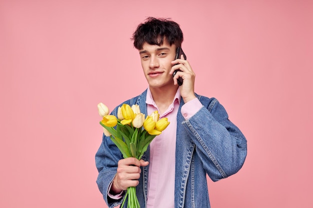 Foto de um jovem namorado romântico em uma jaqueta jeans com um buquê de flores um presente romance de vida