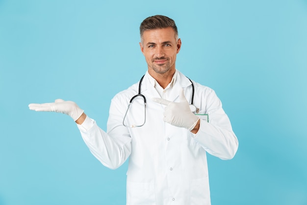 Foto de um médico bonito homem maduro posando isolado sobre a parede azul mostrando copyspace.