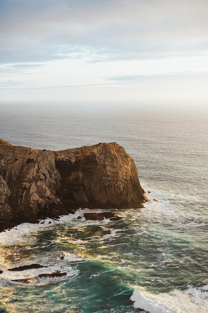 Foto de um penhasco escarpado na costa sul de Portugal As ondas estão batendo forte nele