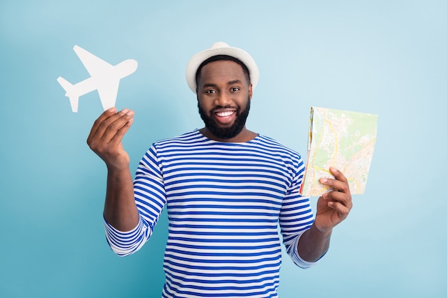 Foto de um viajante engraçado, atraente, de pele escura, segurando o mapa do avião em papel pronto para viajar para o exterior.